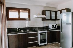 uma cozinha com armários de madeira e um frigorífico em Qavi - Pipa Beleza Resort em Pipa
