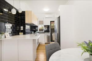 una cocina con encimeras blancas y azulejos negros en Adamstown Short Stay Apartments, en Adamstown