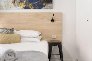 a bedroom with a bed with a wooden headboard and a stool at Adamstown Short Stay Apartments in Adamstown