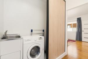 a laundry room with a washing machine and a sink at Adamstown Short Stay Apartments in Adamstown