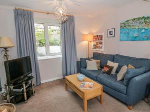 uma sala de estar com um sofá azul e uma televisão em Nathaniel's Cottage em Kirkcudbright