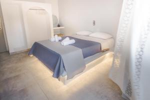 ein Schlafzimmer mit einem Bett mit blauen Laken und weißen Kissen in der Unterkunft Blue Era Apartments in Batsi
