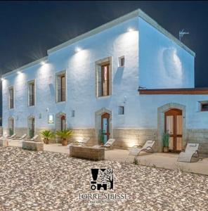 biały budynek z krzesłami przed nim w obiekcie B&B Torre Sibissi Bari w mieście Triggiano