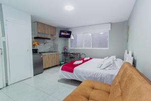 a bedroom with a large bed and a kitchen at ApartaSuites & Hotel Bogota Teusaquillo in Bogotá
