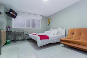 a bedroom with a bed and a tv and a couch at ApartaSuites & Hotel Bogota Teusaquillo in Bogotá