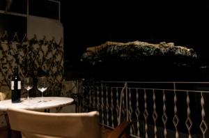a table with two wine glasses on a balcony at night at Luxury penthouse , breathtaking Acropolis view in Athens