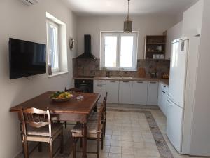 a kitchen with a wooden table and a kitchen with a refrigerator at Captains' house in Vathi