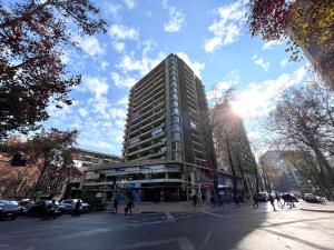 wysoki budynek na ulicy miejskiej z ludźmi przed nim w obiekcie Apartamentos City Centro Los Leones w mieście Santiago