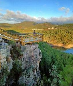 a person standing on a bridge on top of a mountain at Quintinha do Quintas in Valhascos