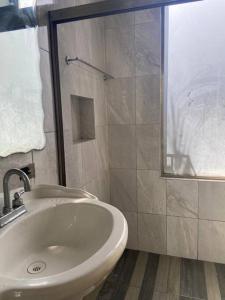 ein Badezimmer mit einem weißen Waschbecken und einer Dusche in der Unterkunft Casa Donde Entra la Luz y Vive la Naturaleza CCTV in Cozumel + 23 Fotos