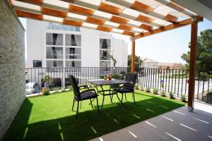 eine Terrasse mit einem Tisch und Stühlen unter einer Pergola in der Unterkunft Solis Apartments Bol in Bol