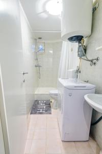 La salle de bains blanche est pourvue de toilettes et d'un lavabo. dans l'établissement MaJo Apartma Punta, à Piran