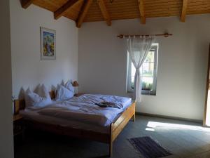 a bedroom with a bed in a room with a window at Platán Panzió in Nyúl