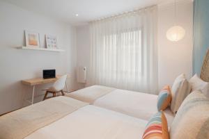 une chambre blanche avec un lit et un bureau dans l'établissement Lido View Calla by An Island Apart, à Funchal