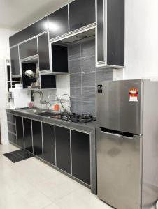 eine Küche mit einem Kühlschrank und Schränken aus Edelstahl in der Unterkunft Mahsuri Homestay in Jitra