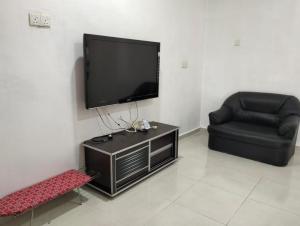 a living room with a flat screen tv and a chair at Mahsuri Homestay in Jitra