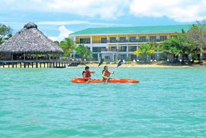 two people in a kayak in the water near a resort at Playa Tortuga Hotel and Beach Resort in Bocas del Toro