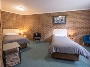 艾爾登的住宿－Eildon Parkview Motor Inn Room 1，一间设有两张床和砖墙的房间