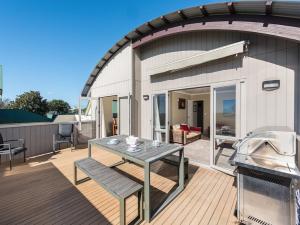 a outdoor deck with a table and a grill at A Beach Barn Haven - Papamoa Holiday Home in Papamoa