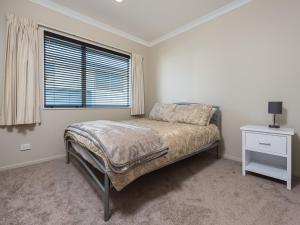 una camera con letto, finestra e comodino di A Beach Barn Haven - Papamoa Holiday Home a Papamoa