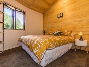 a bedroom with a bed and a wooden wall at Rata - Ohakune Holiday Home in Ohakune