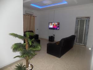 uma sala de estar com duas cadeiras e uma televisão em Great Secured 1Bedroom Service Apartment ShortLet-FREE WIFI - Peter Odili RD - N29,000 em Port Harcourt