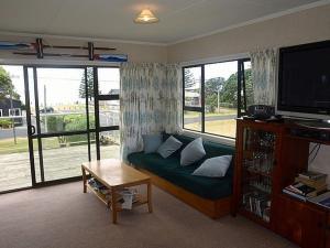 a living room with a couch and a large window at Waihi Beach Break - Waihi Beach Bach in Waihi Beach
