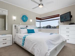 a white bedroom with a white bed and a window at At The Bay - Mt Maunganui Holiday Home in Matapihi