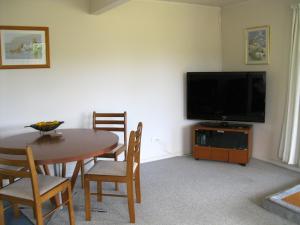 a living room with a table and a television at Cooks Beach Gem - Cooks Beach Holiday Home in Cooks Beach