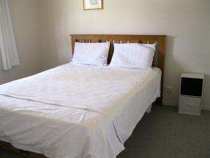 a bedroom with a large bed with white sheets and pillows at Cooks Beach Gem - Cooks Beach Holiday Home in Cooks Beach