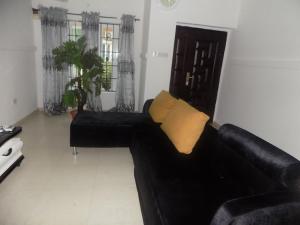 Sofá negro con almohada amarilla en la sala de estar en Unique 1BEDROOM Shortlet Stadium Rd with 24hrs light-FREE WIFI -N35,000 en Port Harcourt
