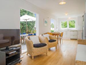 a living room with wicker chairs and a table at Daisy Cottage - Hahei Bach in Hahei