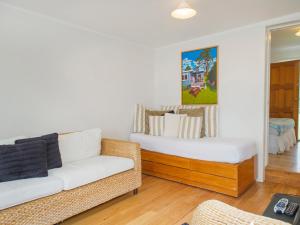 a living room with a couch and a bed at Daisy Cottage - Hahei Bach in Hahei