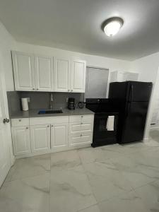 een keuken met witte kasten en een zwarte koelkast bij Guest house near Downtown Miami in Miami
