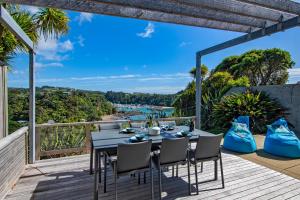 a table and chairs on a deck with a view of the ocean at Marina Views - Tutukaka Holiday Home in Tutukaka