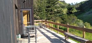 eine Holzterrasse mit einem Tisch und Stühlen auf einem Gebäude in der Unterkunft La Quebrada del Maitén in Navidad