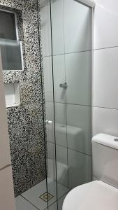 La salle de bains est pourvue d'une douche en verre et de toilettes. dans l'établissement Boca do Rio Hotel, à Salvador