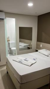 a bedroom with a bed and a bathroom with a mirror at Boca do Rio Hotel in Salvador