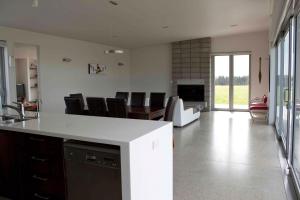 a kitchen and living room with a table and chairs at The Perfect Degree - Sandy Bay Holiday Home in Matapouri