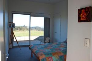 een slaapkamer met een bed en een raam met uitzicht bij The Perfect Degree - Sandy Bay Holiday Home in Matapouri