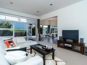 a living room with a white couch and a tv at Magnifique - Mangawhai Holiday Home in Mangawhai