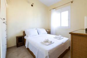 a bedroom with a white bed with two towels on it at The Green Maisonette in Siviri