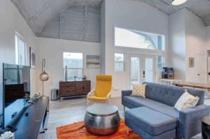 a living room with a blue couch and a yellow chair at Industrial chic barndominium w/ high ceilings in Houston