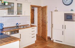 a kitchen with white cabinets and a sink and a refrigerator at Awesome Home In Karwesee With Sauna in Karwesee