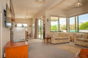 a living room with couches and a refrigerator at Surf Beach Views - Whangamata Holiday Home in Whangamata