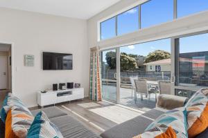 a living room with a couch and a large window at Beach Retreat - Ohope Holiday Home in Ohope Beach