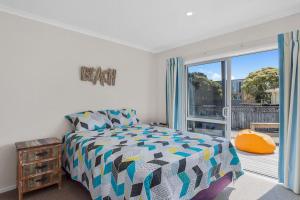a bedroom with a bed and a large window at Beach Retreat - Ohope Holiday Home in Ohope Beach