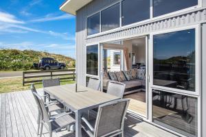 a patio with a table and chairs and a couch at Beach Retreat - Ohope Holiday Home in Ohope Beach