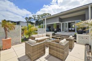 a patio with wicker furniture and a house at Little Pearl of Vista Verano - Mangawhai Home in Mangawhai