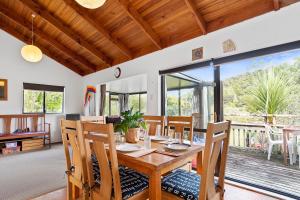 a dining room with a wooden table and chairs at Riverview Retreat - Cooks Beach Holiday Home in Cooks Beach